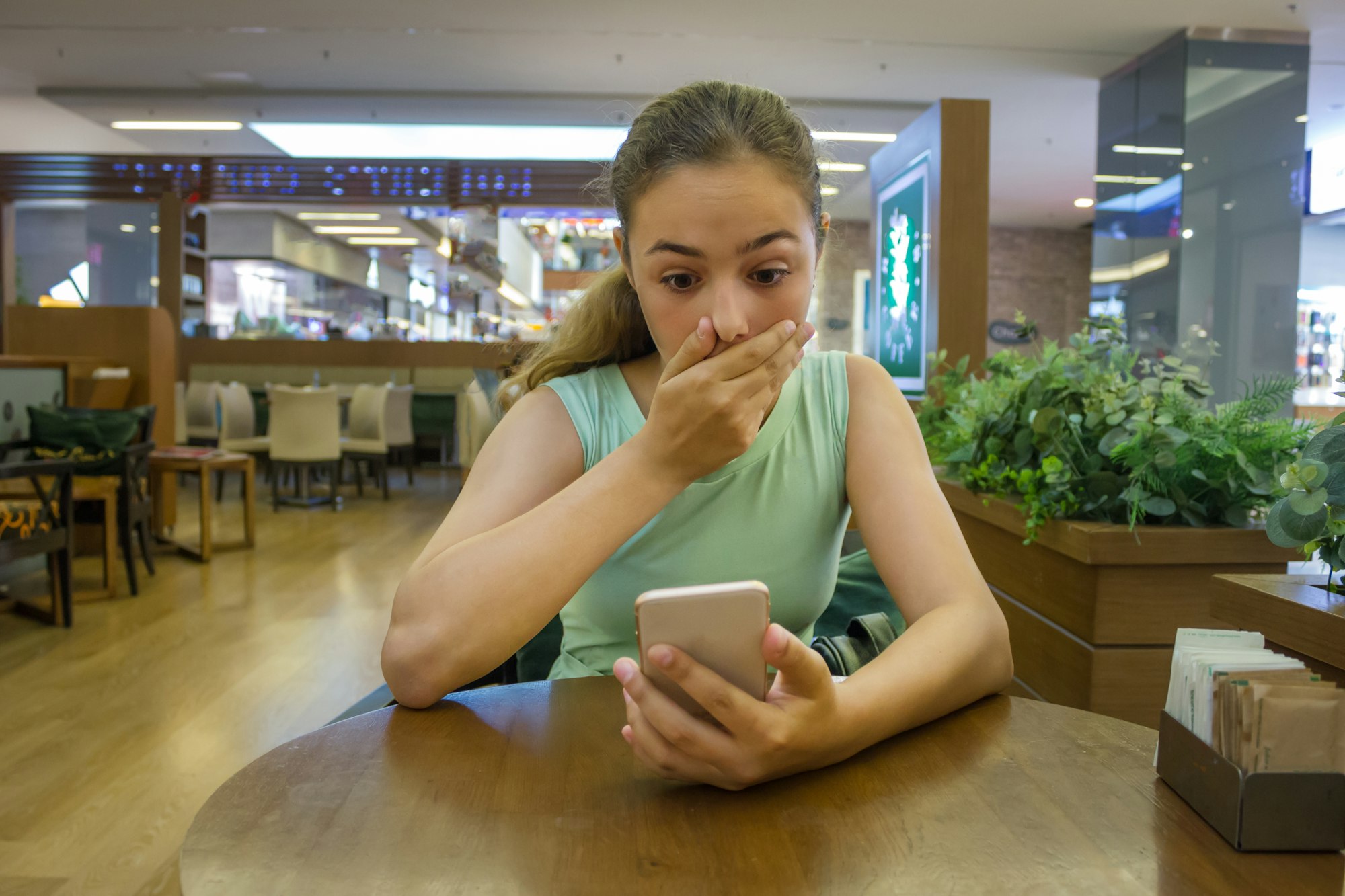 Young pretty teen girl reads shocking news in her phone